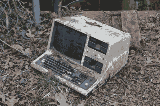 An abanoned and dirty computer from the nineties (the type that has a CRT screen and keyboard built in) lying on a forest floor